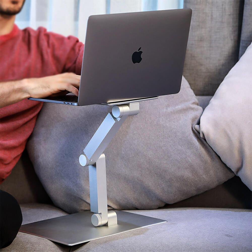 strong and sturdy laptop holder macbook air pro riser, man with red sweater on sofa working with a macbook laptop on an aluminum silver white laptop stand 