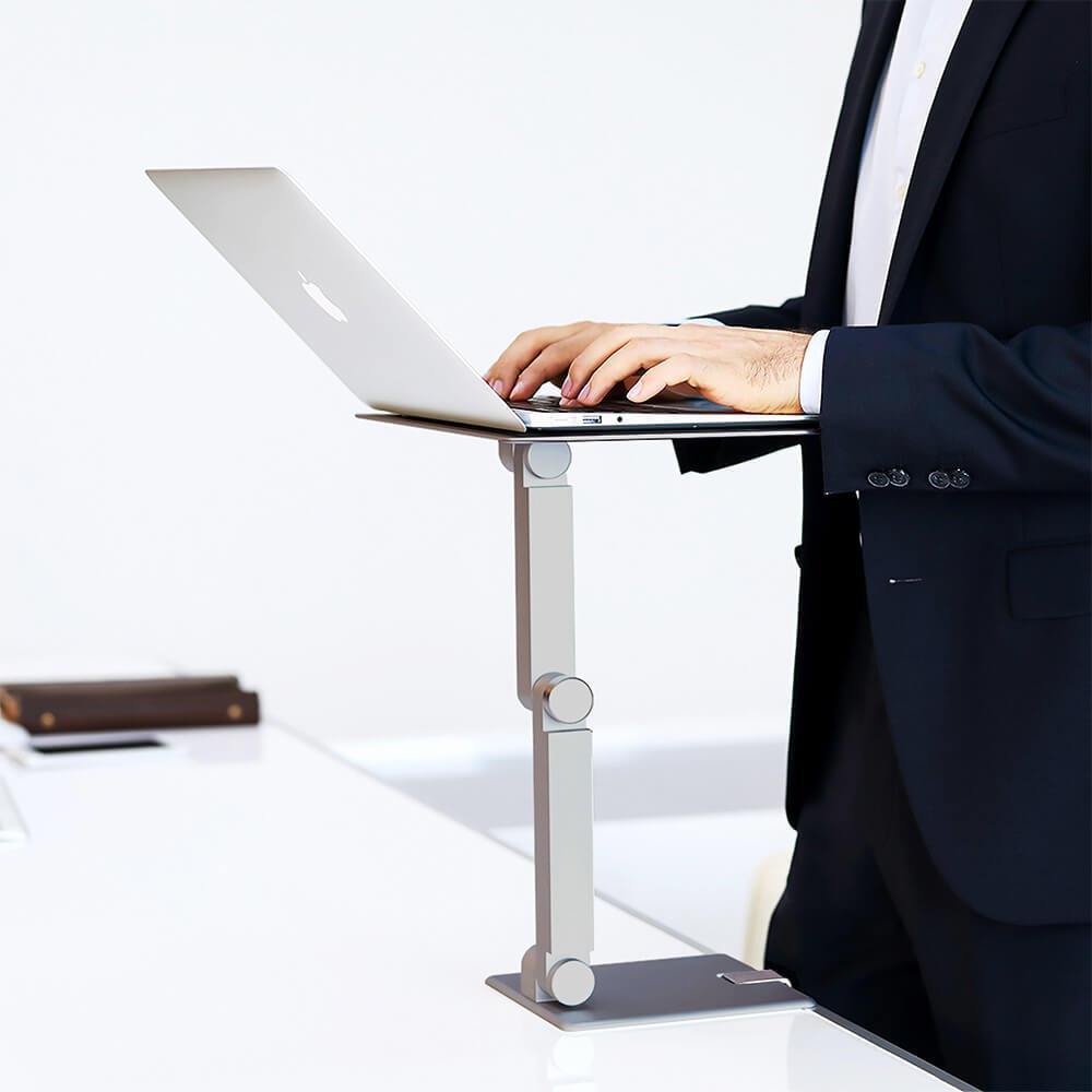 Maxtand laptop stand space gray, man wearing shirt and suit standing and typing on a macbook laptop with a sturdy aluminum macbook holder, sit to stand, standing work, not stationary in office 